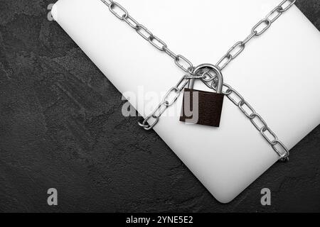 Padlock with laptop and chain on dark grunge background Stock Photo