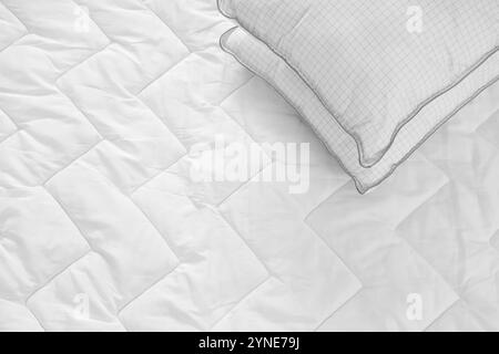 Soft pillow on quilted white blanket as background Stock Photo