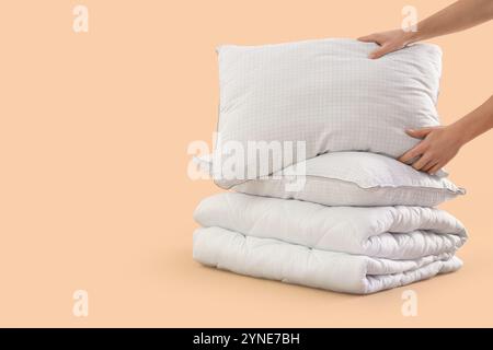 Male hands with folded soft blanket and pillows on beige background Stock Photo
