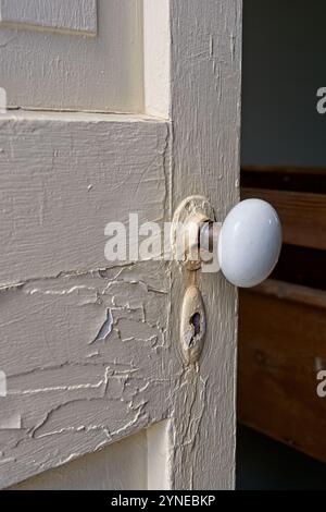 Weathered old panel door left ajar with peeling paint Stock Photo