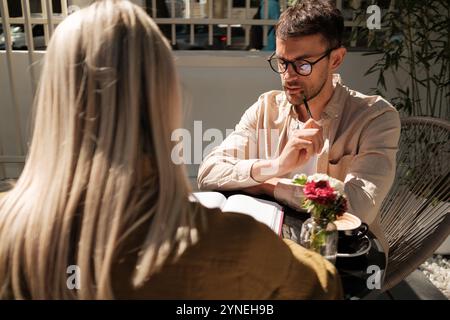 Casual meeting between colleagues discussing work in a cozy outdoor cafe Stock Photo