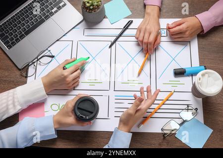 Developing UI design. Designers creating website wireframe on paper at wooden table, top view Stock Photo