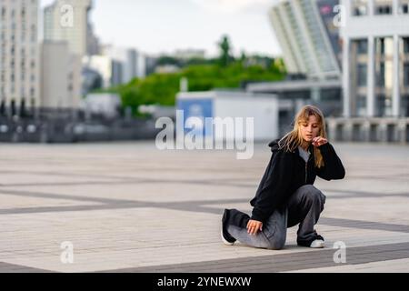 Young dancer practicing movements on urban plaza during daylight hours Stock Photo