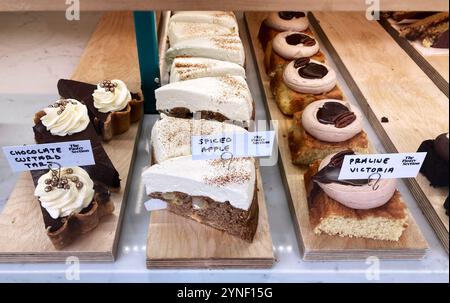 Chocolate Custard Tart, Spiced Apple Cake and Praline Victoria in a bakery shop window Stock Photo