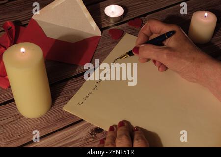 Woman handwriting a love letter with candles and romantic decorations Stock Photo