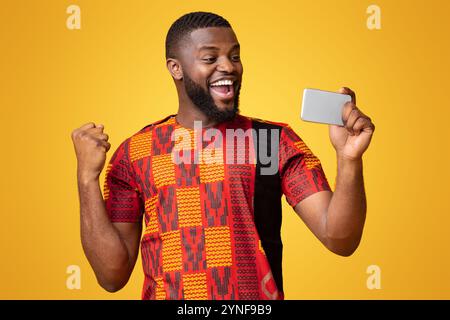 Happy black man holding phone and expressing happiness Stock Photo