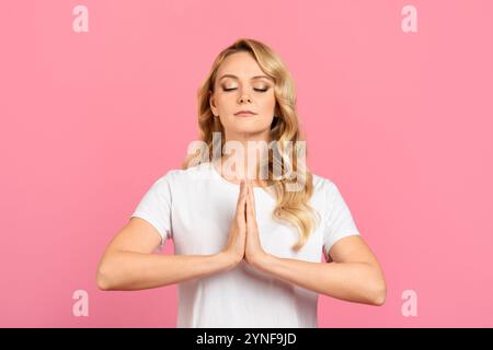 Woman practicing mindfulness meditation with hands in prayer position Stock Photo
