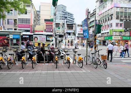 Corner of Xinyi Road and Yongkang Street in Taipei, Taiwan; different modes of transportation; scooters, bus, bicycles, pedestrians crossing roadway. Stock Photo