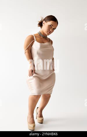 A young woman with short stature poses gracefully in an elegant dress, highlighting diversity. Stock Photo