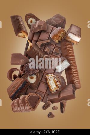 Different chocolate products in air on light brown background Stock Photo