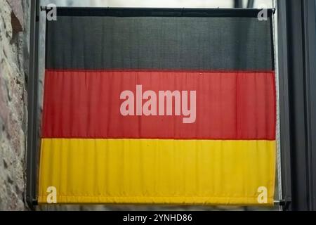 Deutsche Flagge im modernen Innenbereich , Deutschland, 23.11.2024, Die deutsche Flagge hängt in einem modernen Innenbereich vor einer Steinwand und symbolisiert nationale Identität in einem eleganten Kontext. *** German flag in a modern interior , Germany, 23 11 2024, The German flag hangs in a modern interior in front of a stone wall and symbolizes national identity in an elegant context Stock Photo