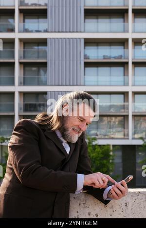 mature man in classy suit browsing on smartphone Stock Photo