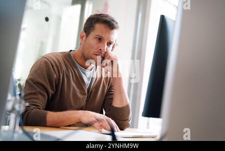 Portrait of a disappointed man programmer looking stressed out while working on a computer code Stock Photo