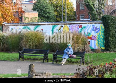 woman sitting on a bench in queens park loughborough leicestershire Stock Photo