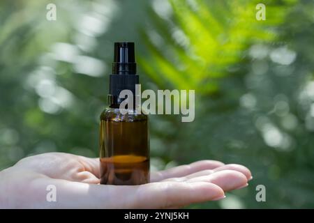 Hand Holding Amber Spray Bottle Outdoors Stock Photo