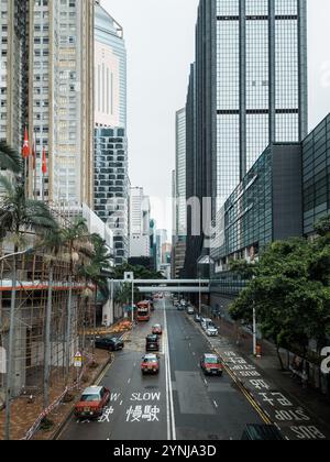 Modern Urban Street Scene with High-Rise Buildings, Traffic, and Red Double-Decker Buses Amidst a Vibrant Cityscape. Stock Photo