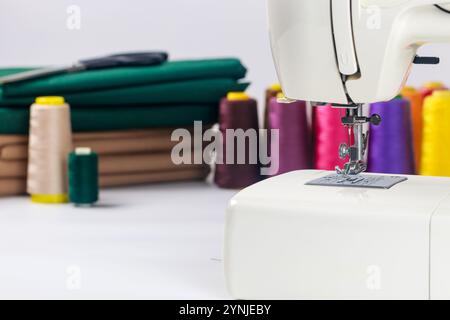 Sewing machine with colorful thread spools and fabric in bright crafting space Stock Photo