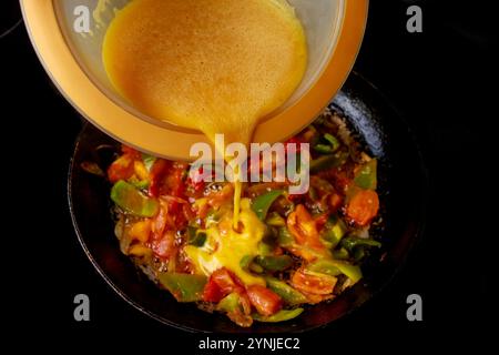 Cooking colorful vegetable omelette in skillet at home with fresh ingredients Stock Photo