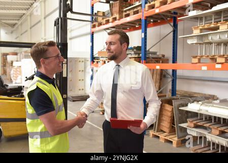 Worker and Manager in a warehouse in the logistics sector - handshake in the morning to start working in a new job Stock Photo