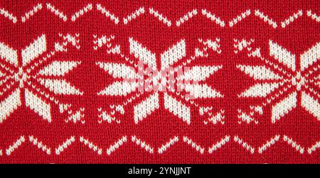 White color eight pointed star knitted pattern on sweater. White stars on red background, studio shot, indoors. Stock Photo