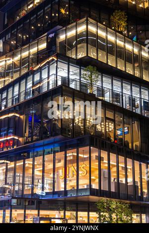 Modern glass office building exterior at night showing people working Stock Photo