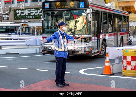 Japanese security guard wearing face mask directing traffic in tokyo Stock Photo