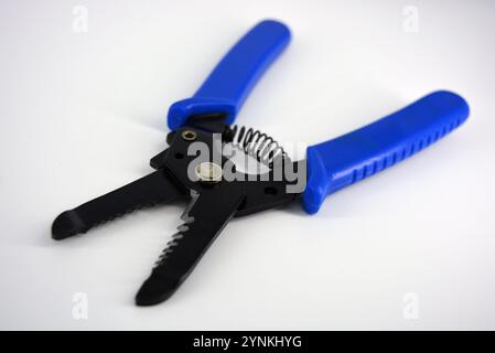 Metal plassentes with blue plastics handles for trimming wires of different diameter located on a white plastic background. Stock Photo