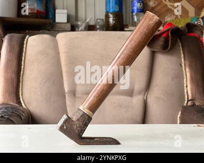 A hand tool with a wooden handle rests on a table in a workshop setting. Stock Photo