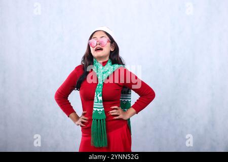 portrait of Asian ladies wearing red sweater with Santa hat and scarf celebrating merry christmas, crying sobbing to the upper right wearing red glass Stock Photo