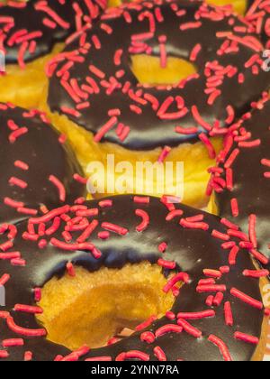 Goiania, Goias, Brazil – November 25, 2024: A set of decorated donuts, covered in chocolate with colorful sprinkles on top. On display for sale. Stock Photo