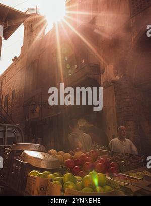 people walking in old Cairo Infront of a cart full of fruits Stock Photo