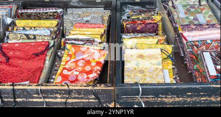 Japanese textiles collection at a shop display, Variety of fabrics with ornate patterns and vibrant colors folded on wooden cases Stock Photo