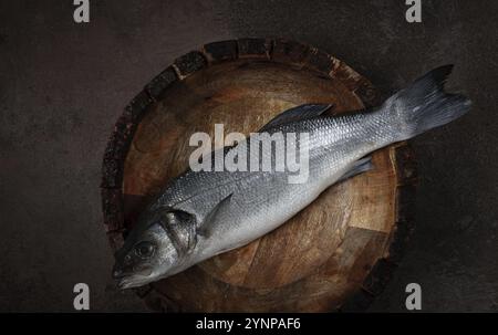 Fresh, raw sea bass fish, in a wooden plate, top view, no people. Stock Photo