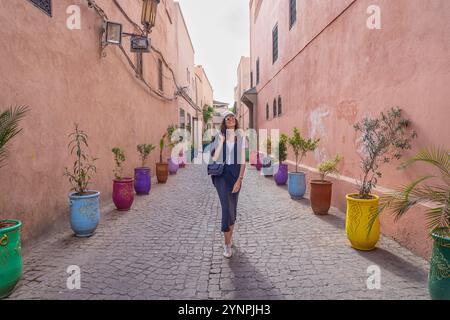 Young Dark Haired Woman Walking in Red Streets of Marrakech Surrounded by Colorful Pots, Morocco Stock Photo
