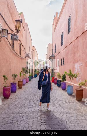 Young Dark Haired Woman Walking in Red Streets of Marrakech Surrounded by Colorful Pots, Morocco Stock Photo