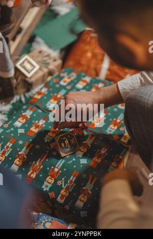 Unwrapping gifts from under the Christmas tree. Gift wrapped in colorful paper. Christmas atmosphere Stock Photo