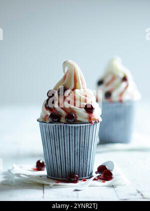 Two frozen yoghurt ice creams refined with Amarena cherries on a white wooden table Stock Photo