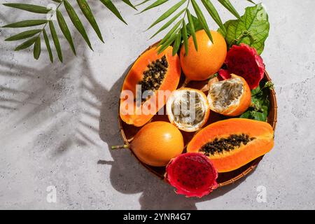 exotic tropical fruits,  passion fruits and dragon fruit, ripe papayas. on a bamboo tray with green leaves, stone background Stock Photo