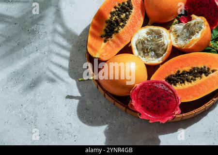 exotic tropical fruits,  passion fruits and dragon fruit, ripe papayas. on a bamboo tray with green leaves, stone background Stock Photo