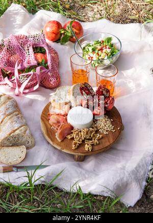 life view picnic scene featuring fresh pomegranates, walnuts, pine nuts, and creamy white cheese displayed on a wooden board, natural sunlight pomegra Stock Photo