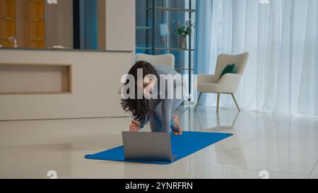Yoga class with laptop workout video tutorial online training at home fit Caucasian woman sport trainer girl yogi female sportswoman doing exercise Stock Photo