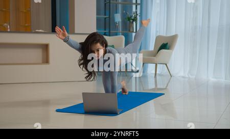 Yoga class with laptop workout video tutorial online training at home fit Caucasian woman sport trainer girl yogi female sportswoman doing exercise Stock Photo
