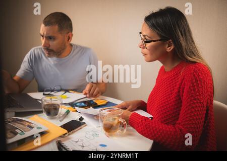 Two people are sitting at a table with a laptop and a cup of coffee Stock Photo