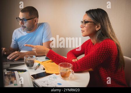 Two people are sitting at a table with a laptop and a cup of tea, couple organizing credit documents .New home concept. Stock Photo