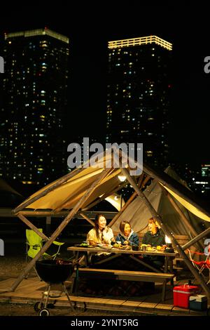 Three smiling women in their 20s having outdoor dinner Stock Photo