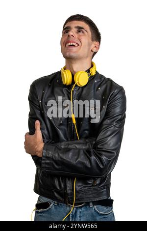 Happy young man wearing yellow headphones and a black leather jacket, smiling and looking upwards Stock Photo