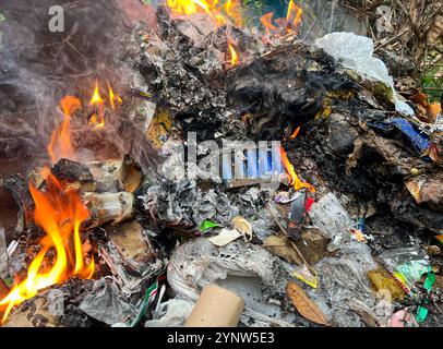 Philippines pollution problem: melted plastic & E waste, electronics burned among household trash, lithium battery in fire, technologic dump, landfill Stock Photo