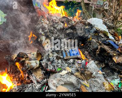 Philippines pollution problem: melted plastic & E waste, electronics burned among household trash, lithium battery in fire, technologic dump, landfill Stock Photo