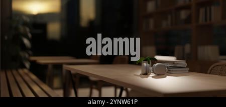 A close-up of headphones and stack of books on a wooden table in a comfortable minimalist library at dusk with the warm, soft lighting creates a cozy Stock Photo