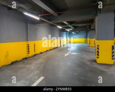 A spacious and well lit underground parking garage features bright yellow and gray walls for a modern feel Stock Photo
